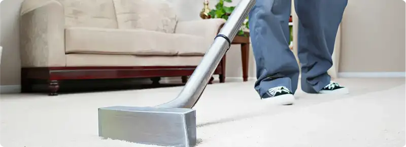 Carpet cleaning technician using a hot-water extraction wand on a light-colored carpet in a living room, Clearwater, FL.
