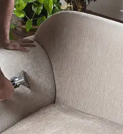 Professional upholstery cleaner deep-cleaning a fabric sofa with a handheld extraction tool and hose Clearwater, FL.